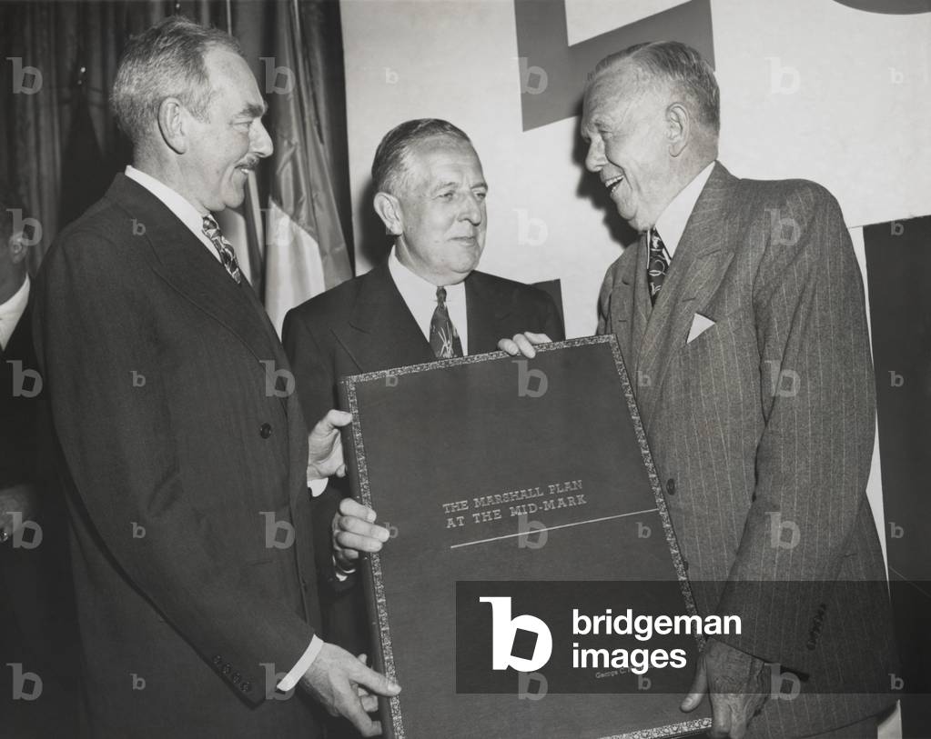 Celebration of the 2nd Anniversary of the Marshall Plan. Secretary of State Dean Acheson (left) and Economic Cooperation Administrator Paul Hoffman (center) present George Marshall a large bound report on operation of the Marshall Plan. April 3, 1950.