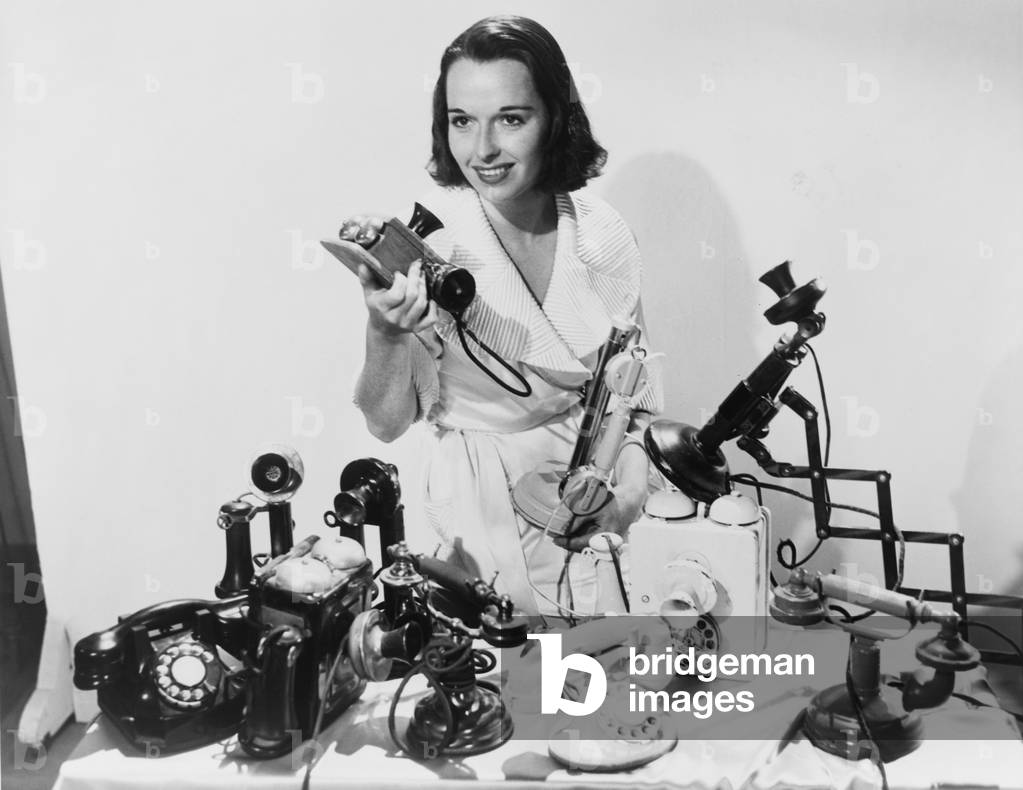 Louise Brooks (1906-1985), popular silent film actress, posing with ten telephones, some old models as well as the most up to date 1936 models