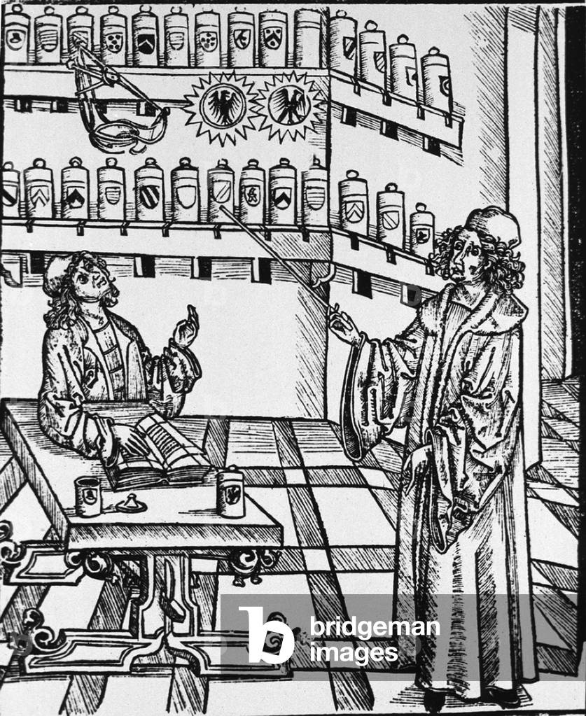 A pharmaceutical lesson showing the master, pointing to shelves of apothecary jars, instructing the apprentice at a table with an open book. Woodcut from MEDICINARIUS. DAS BUCH DER GESUNTHEIT (Book of Health), by Hieronymus Brunschwig, c. 1505