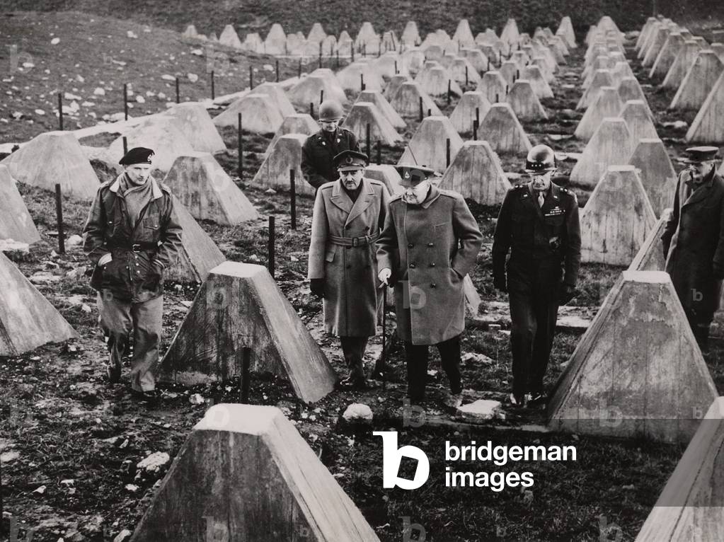 Winston Churchill walks among the dragons teeth (tank traps) of the fallen Siegfried Line. With him are British Field Marshal Montgomery, British Field Marshal Sir Alan Brooke, and U.S. General William H. Simpson. March 1944