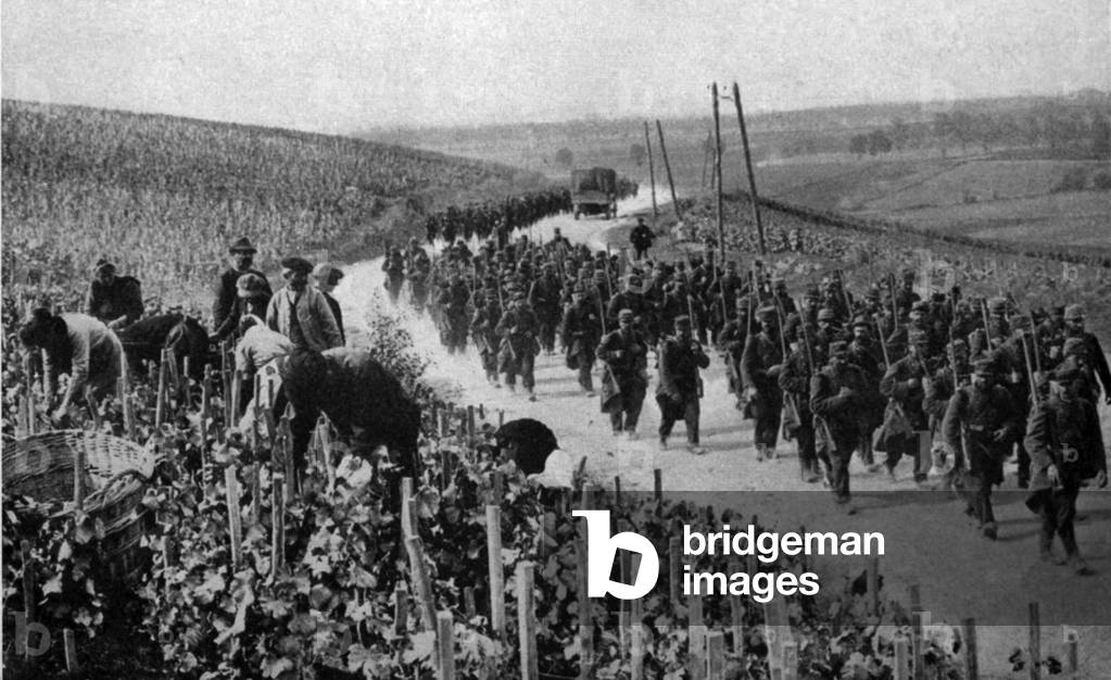 World War 1. Civilians working in a vineyard of the Champaign region of France as troops march past. Possibly during the Battle of the Marne. c. September 6-12, 1914