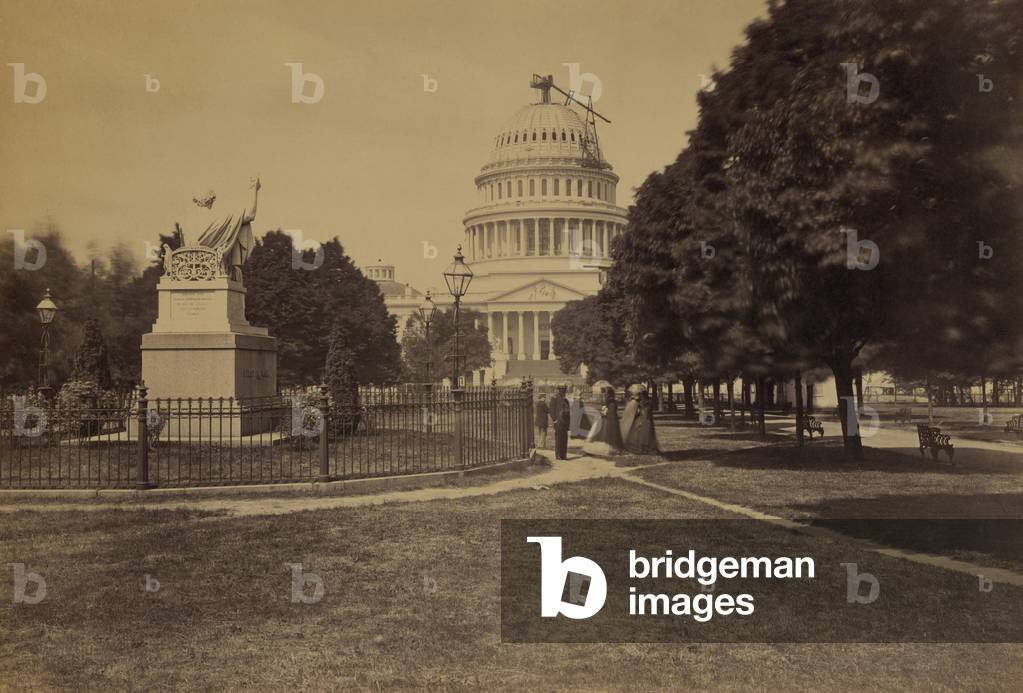 United States Capitol Building in 1863, with the new dome under construction and statue of George Washington by Horatio Greenough in the foreground, where men and women stroll. Photo by Andrew J. Russell