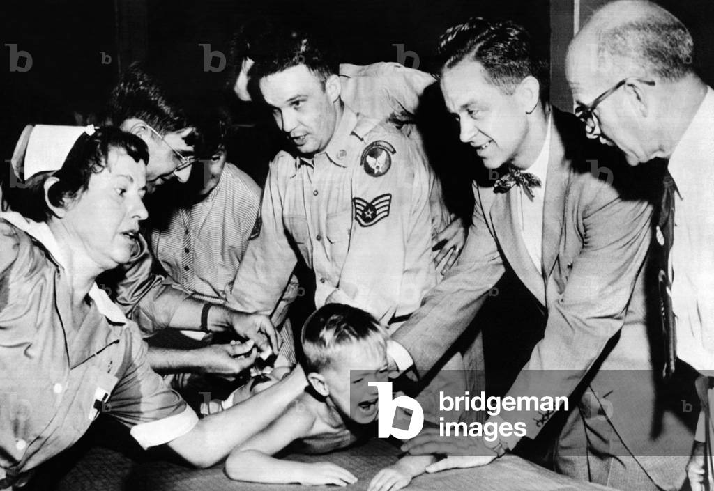 Several doctors and nurses restrain young Ernest Booth. Booth was one of 30,000 children receiving gamma globulin inoculations during polio epidemic in Houston, Texas. June 30, 1953