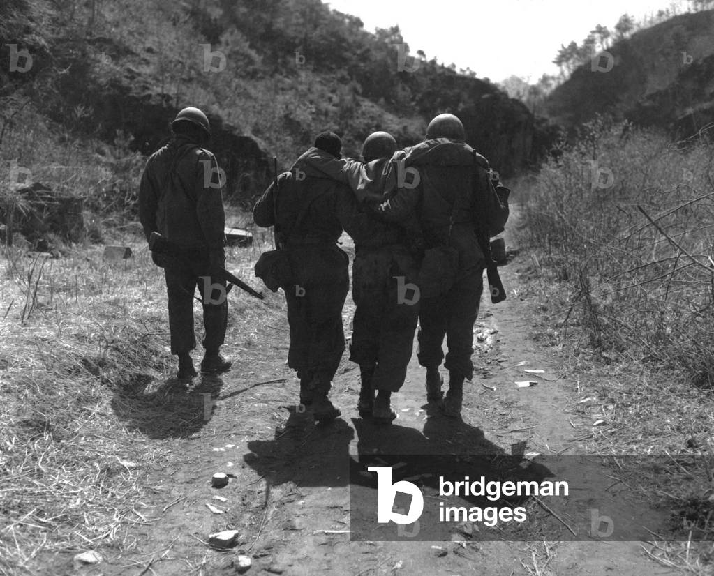 U.S. soldiers aid wounded man of 24th Infantry Regiment. Following a battle 10 miles south of Chorwon, in Central Korea, in the UN defense against the Chinese spring Offensive. April 22, 1951. Korean War, 1950-53