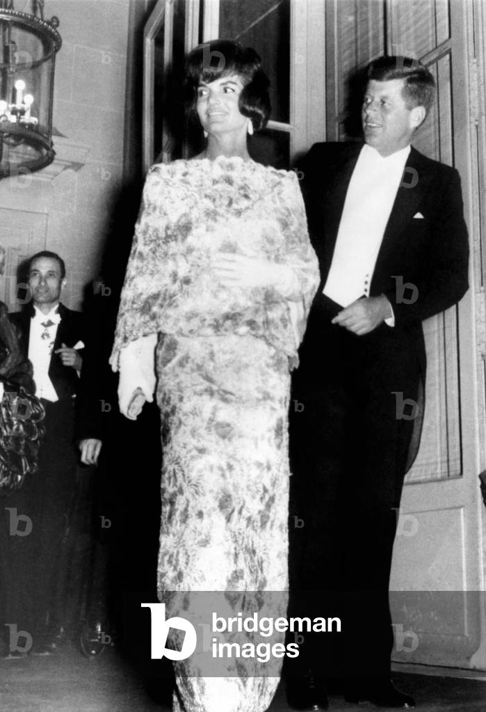 President and Jaqueline Kennedy in Paris. The First Lady wears and white and pink straw lace evening dress during their visit to Paris. They are leaving the French Foreign Ministry for a reception at Elysee Palace. May 31, 1961