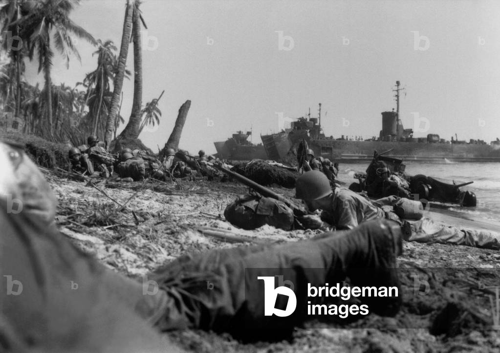 U.S. Sixth Army soldiers lie low on Leyte Island's beach, but they met little Japanese opposition. Landing barges are in the distance. Oct. 20, 1944. Philippines, Pacific Ocean, World War 2