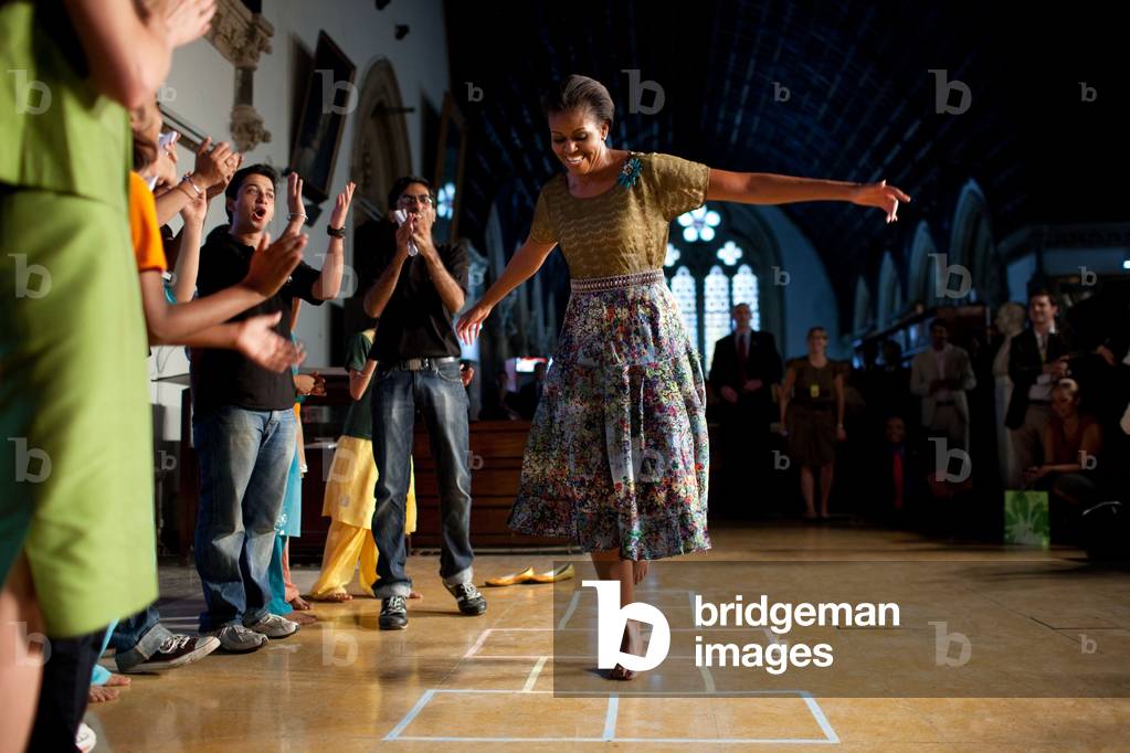First Lady Michelle Obama plays hopscotch during the 'Make A Difference' program at the University of Mumbai in Mumbai India. Michelle wears a tiered floral skirt and moss olive lace top by J. Crew and a broach by Erickson Beamon. Nov. 6 2010.,