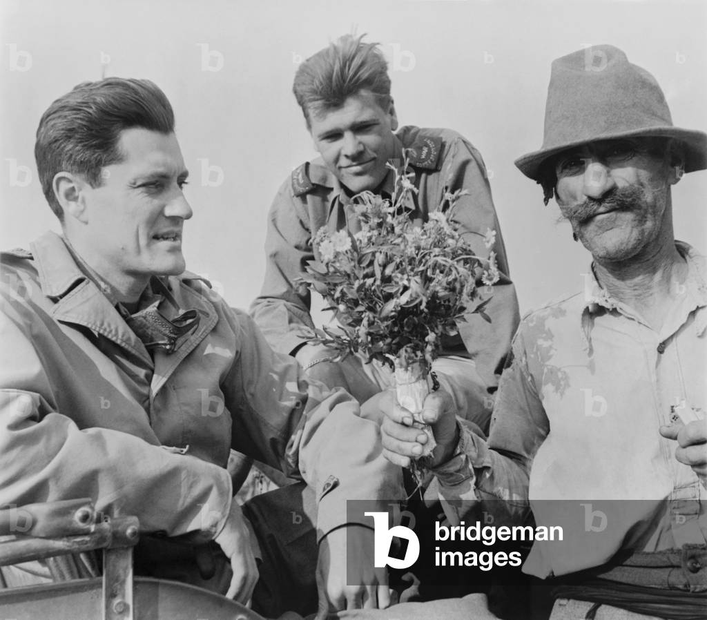 CBS News correspondent Eric Sevareid reporting from Italy during World War 2. He receives flowers from Italian peasant on June 20, 1944. fellow journalist, Newbold Noyes, observe the event