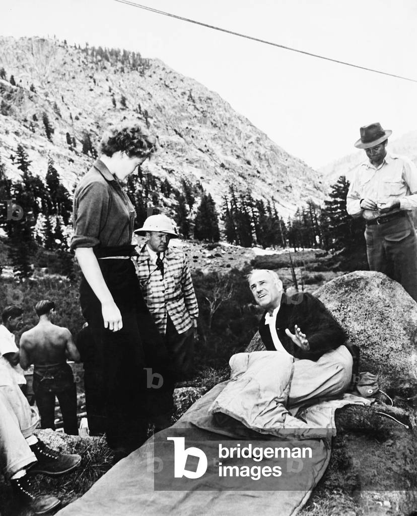 FOR WHOM THE BELL TOLLS, from left: Ingrid Bergman, cinematographer Ray Rennahan (pith helmet), director Sam Wood, Gary Cooper (rear) on set, 1943