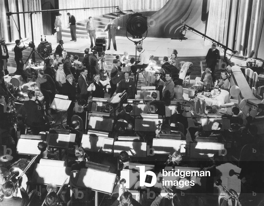 GO INTO YOUR DANCE, Al Jolson (blackface), Leo Forbstein (raised arms) and the studio orchestra on set, 1935