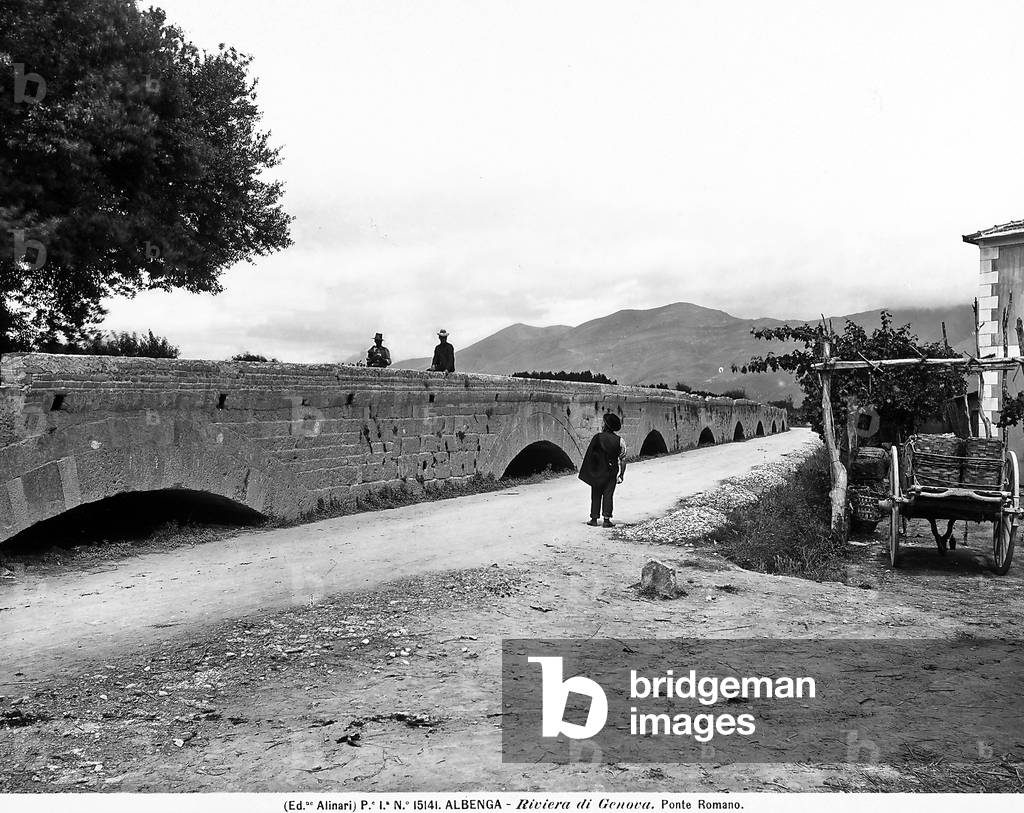 View of the Roman bridge in the environs of Albenga, Province of Savona. The construction skirts an excavated street with some people, on the right, a cart is visible.