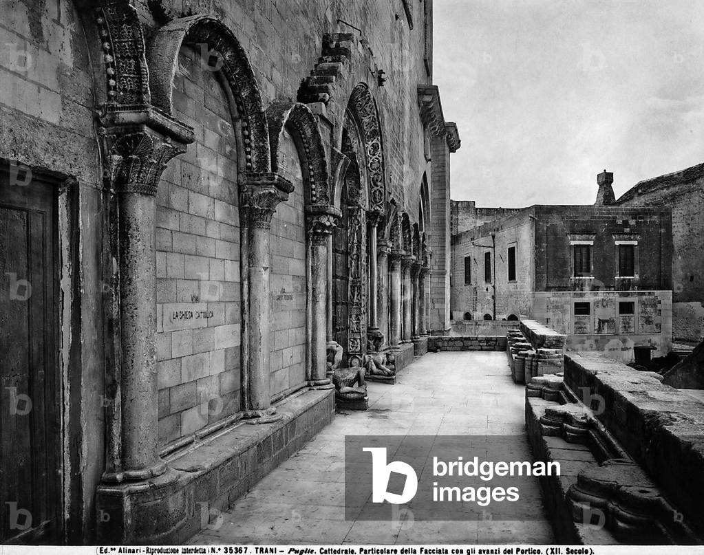 View of the façade of the Cathedral of Trani, in Puglia. On the terrace opposite the façade are some ancient ruins of an atrium and in the background is a house.