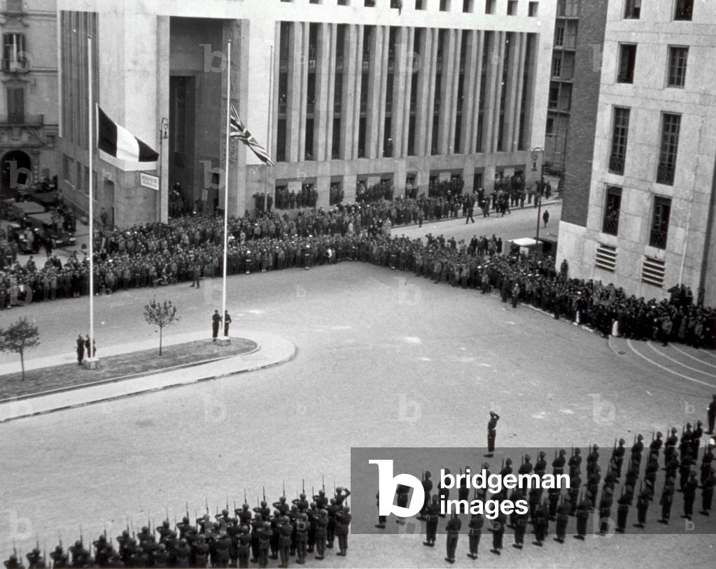 Withdrawal ceremony of the English allied troops in front of the Palazzo della Provincia in Naples. The soldiers, standing to attention, honour the Italian and English flags hoisted on flagstaffs