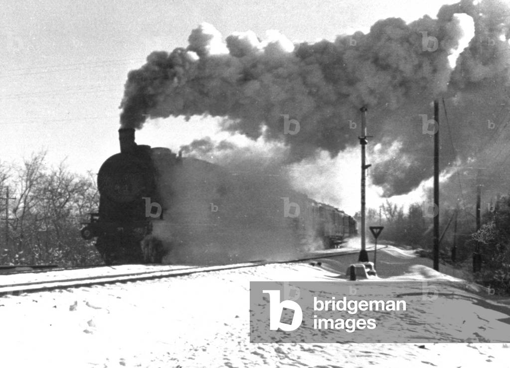 A stretch of railroad with a steam engine in a snow-covered plain in Russia