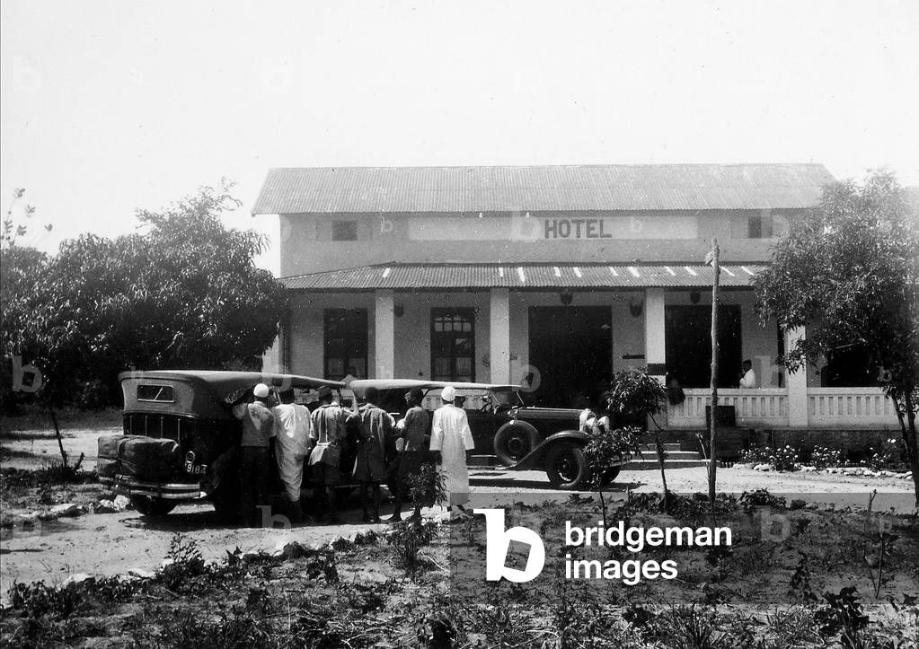 A group of people with cars, in front of a hotel in Dodoma, 1920-1940 (print on double-weight paper)