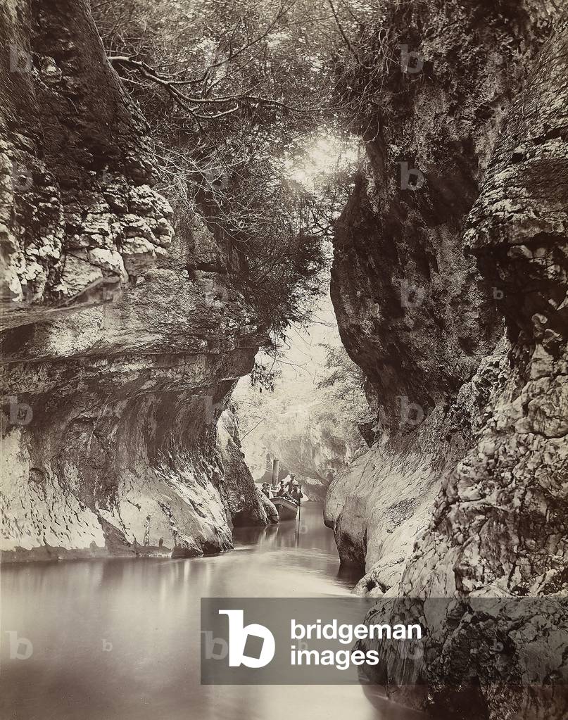 A group of people on board a boat going down a river which runs through a narrow, rocky gorge