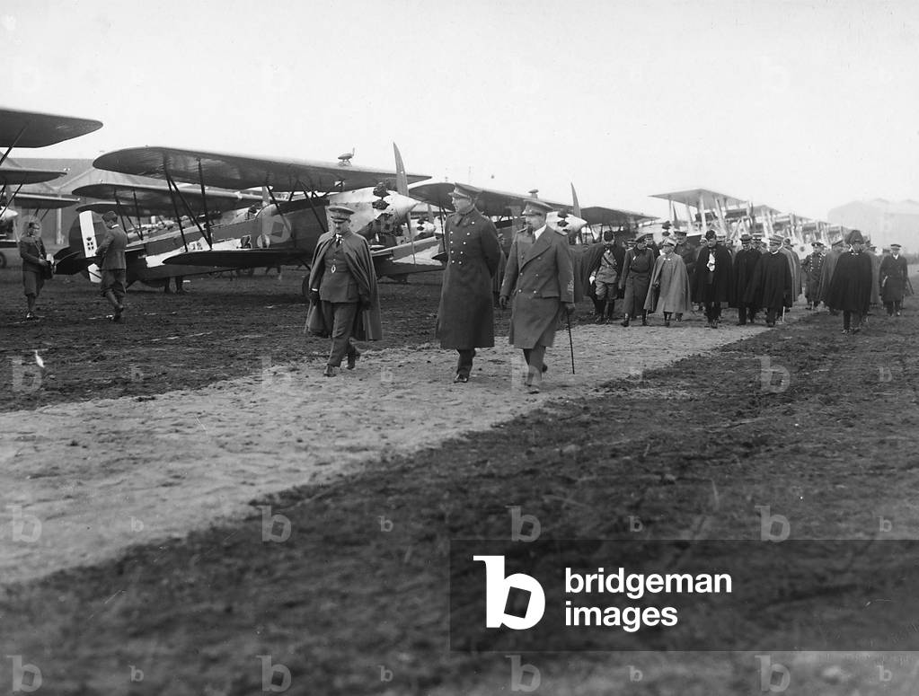 The image shows H.M. King Albert of Belgium, the deputy Italo Balbo, H.M. Boris III of Saxony-Cobourg-Gotha, king of Bulgaria, and Vittorio Emanuele III, king of Italy. The historiacal figures are visiting a military airport. (b/w photo)