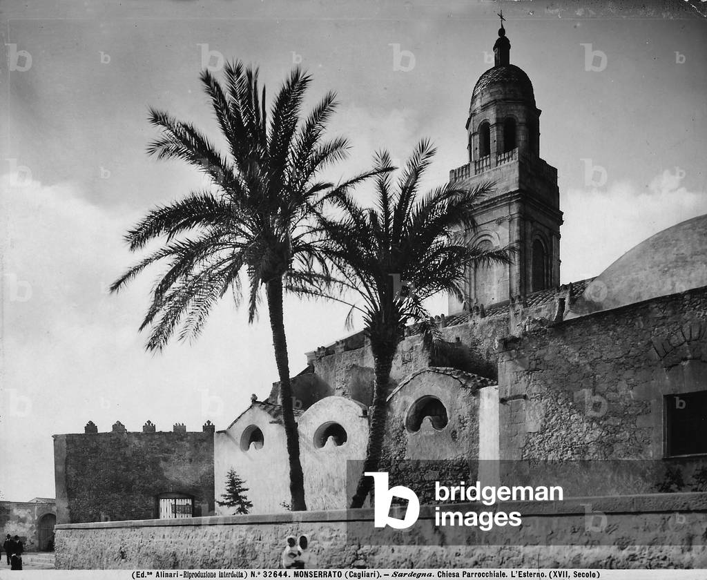 Exterior of the Parish Church of Sant'Ambrogio, Monserrato, environs of Cagliari. Some passersby are visible in the foreground.
