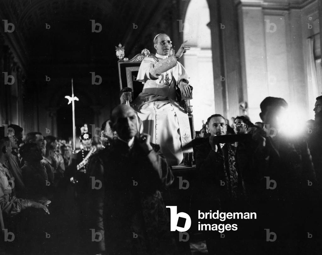 Pope Pio XII being carried to the hall of benediction and blessing American troops lining the aisle (b/w photo)