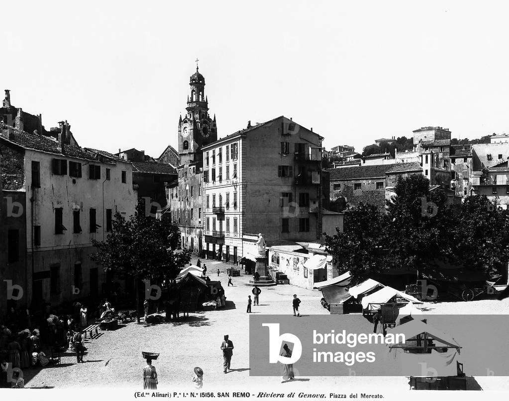 View of the Piazza del Mercato, San Remo, province of Imperia. In the foreground are some stands with passersby, a church and some houses are in the background.