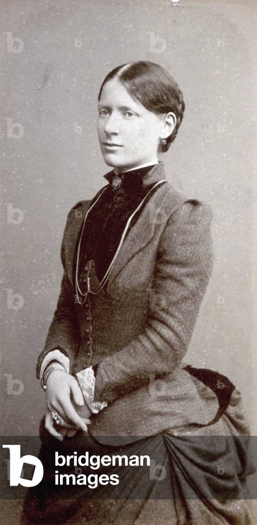 Three-quarter length portrait of a young woman in elegant late nineteenth century day dress