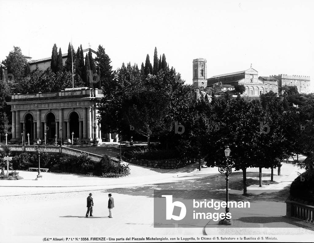 Partial view of Piazzale Michelangelo. The gallery, the Church or San Salvatore and the Basilica of San Miniato are in the background. Two men are chatting on the street.