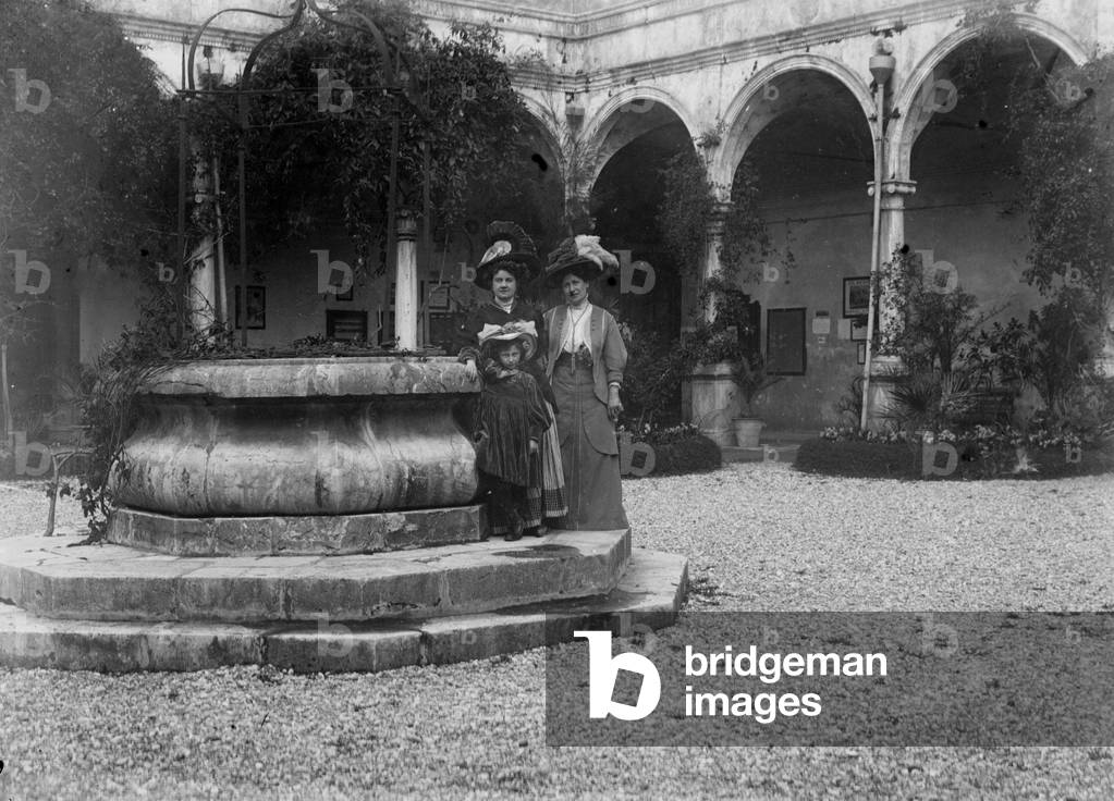 Pair of ladies with baby photographed inside a cloister
