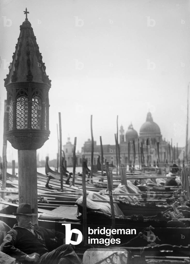 Portrait of a man in a gondola in Venice. In the background the church of Santa Maria della Salute