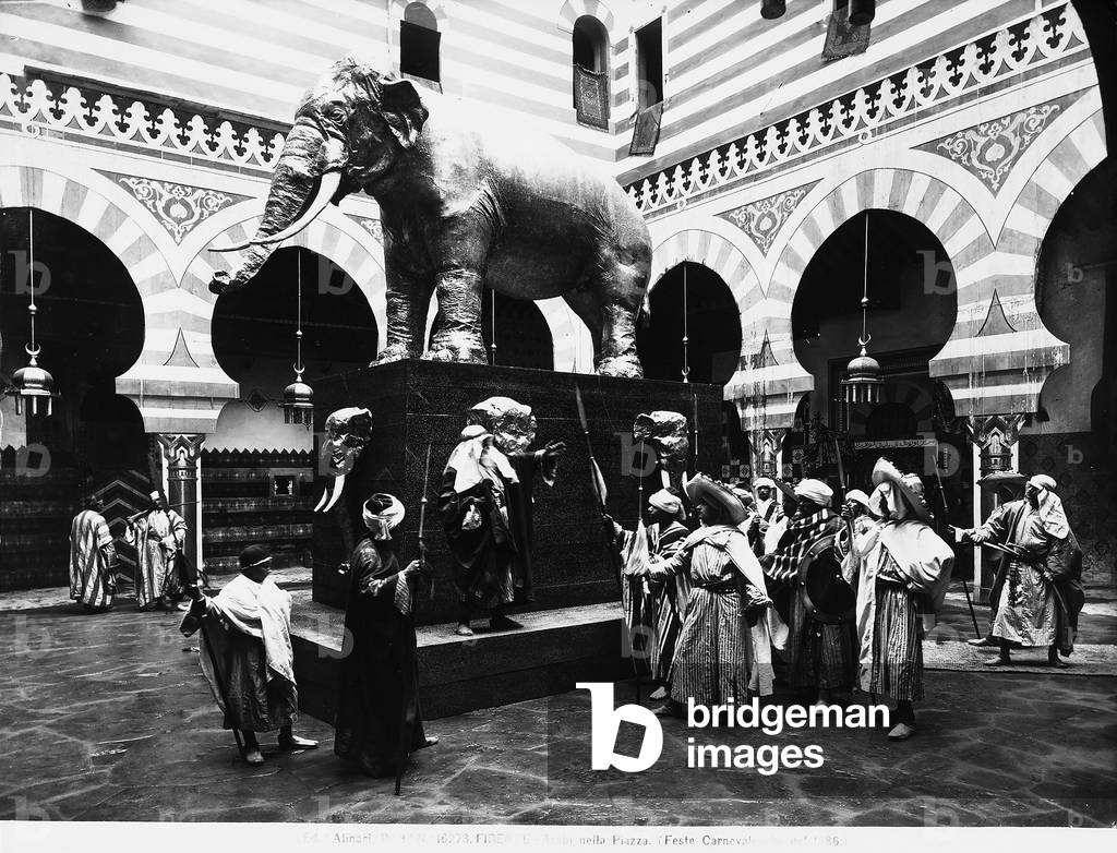 Men dressed as Arabs, seen near a statue of an elephant, during the Carnival festivities held in Florence in 1886