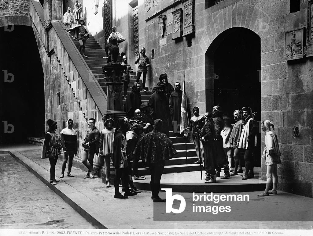A group of people in historic costume posing on the stairs of the courtyard, at present-day Museo Nazionale del Bargello, in Florence