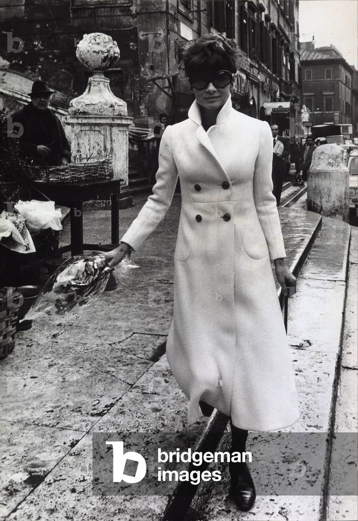 The actress Audrey Hepburn walking in the Piazza di Spagna with a bouquet of flowers in her hand.