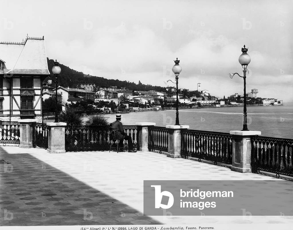 Panorama of the Fasano health resort on Lake Garda. A seated man is admiring a view of the lake in the foreground.