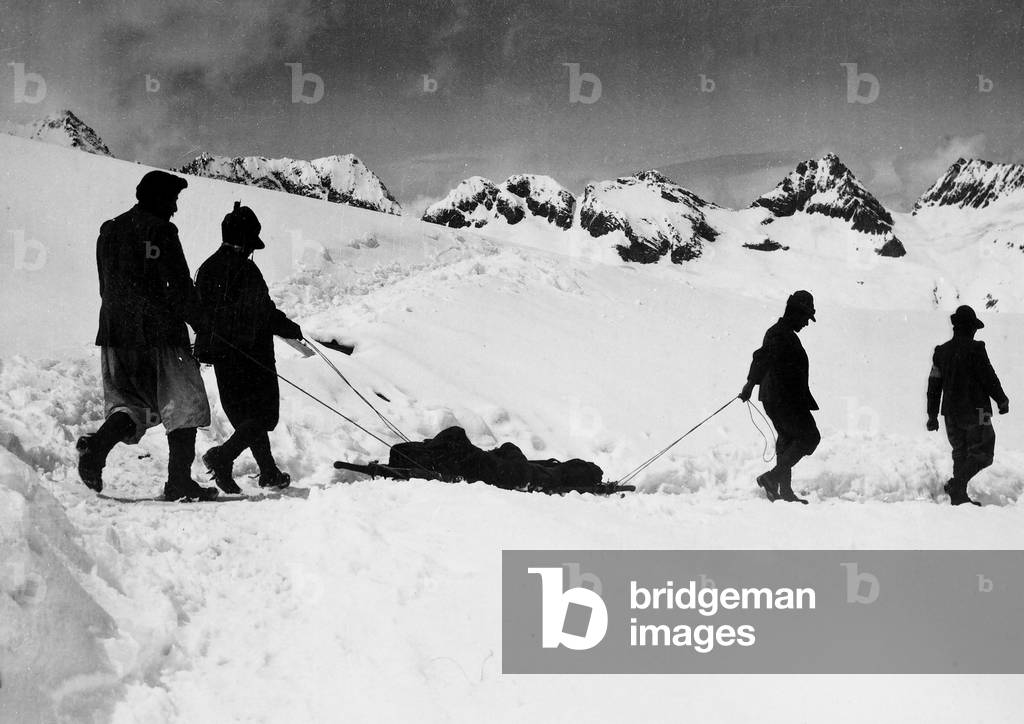 Italian Alpine soldiers transport a wounded person on Adamello during World War I (b/w photo)
