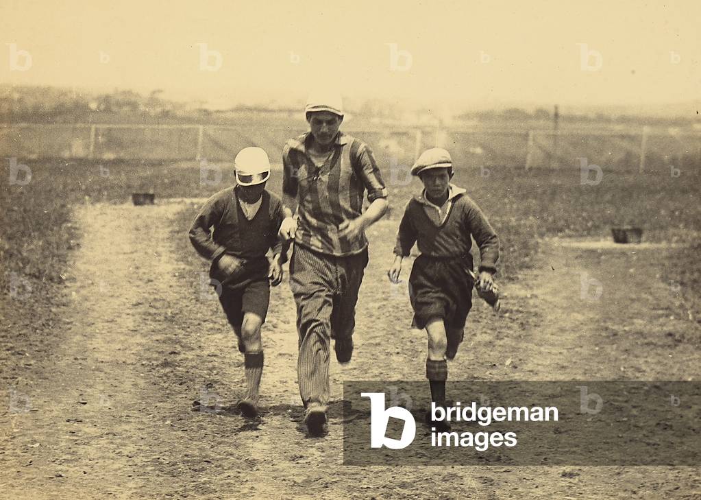 A man and two boys, portrayed while running in a playing field.