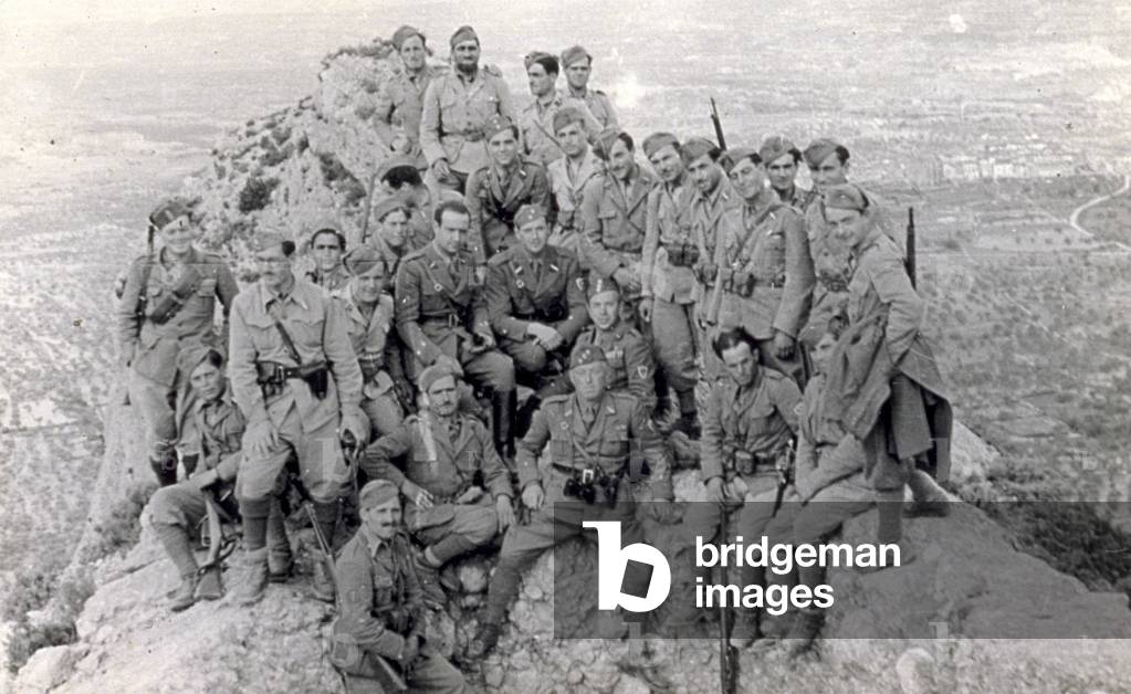 Portrait of a group of Italian soldiers photographed at San Hermita, Horta de San Juan in May 1938. The men in uniform, both standing and seated, are posing on a rocky outcrop of a mountain. A glimpse of the plain below can be had in the background, 05/1938 (b/w photo)