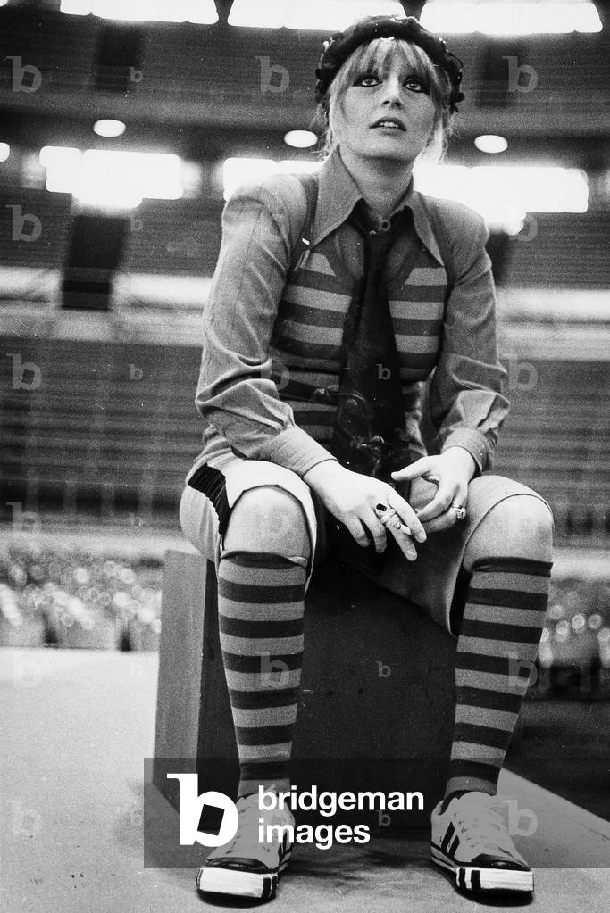 Gabriella Ferri shown in costume, seated on a theatrical stand.