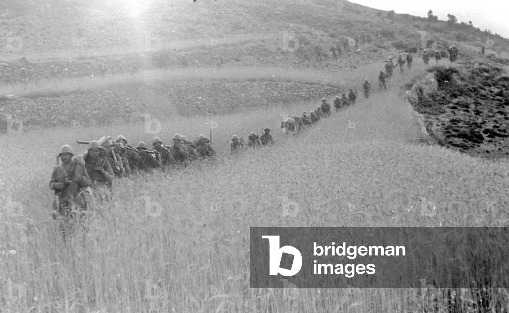A column of Italian soldiers moving towards the town of Pina on July 16, 1938, in the course of the action known as 'Del Levante', during the Spanish civil war. The men, carrying their equipment, are crossing a sunlit field of wheat (b/w photo)