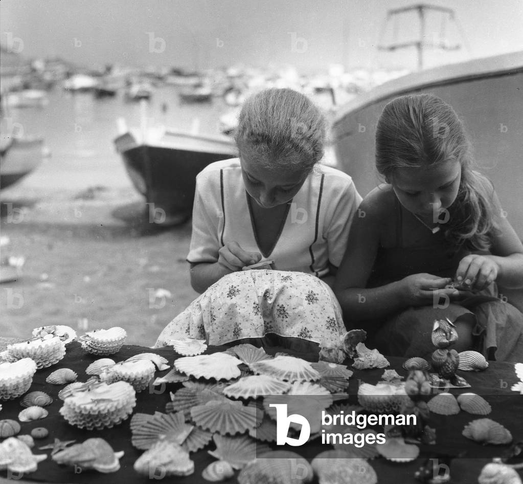 Pair of girls that decorate shells in Porto Ercole in Monte Argentario (b/w photo)