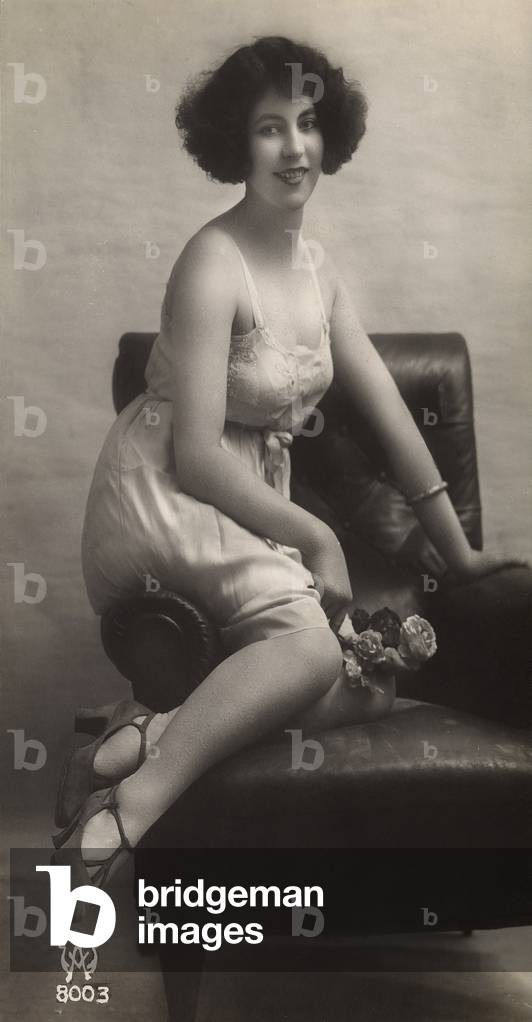 A young woman posing in her petticoat, sitting in a armchair