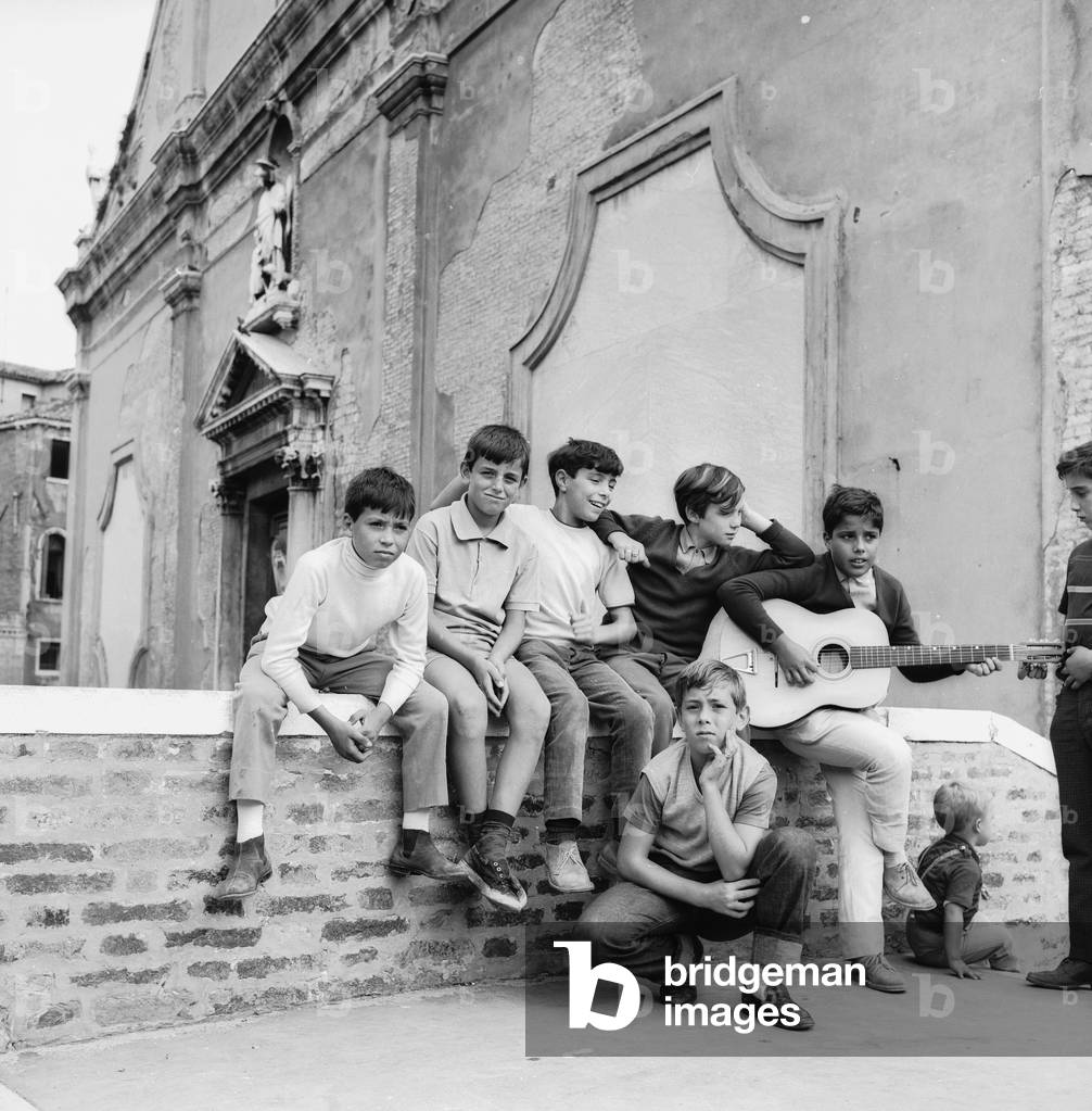 Group of children singing and playing guitar on a bridge in Venice (b/w photo)