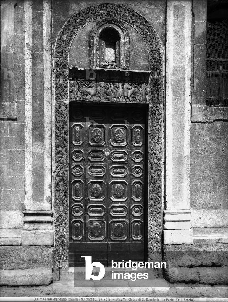 Entrance door of the Church of S. Benedetto in Brindisi. The work is framed by a sculpted band with weavings. The lintel represents battle scenes between men and dragons, surmounted by a small niche.