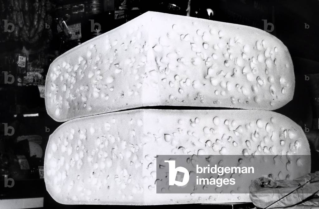 Two large wedges of Gruyere cheese stacked on a counter in a market