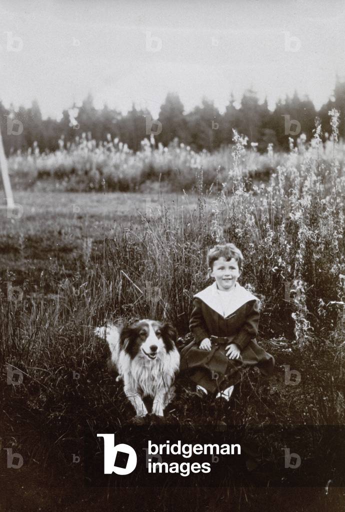 Portrait of a child sitting in a field with his dog