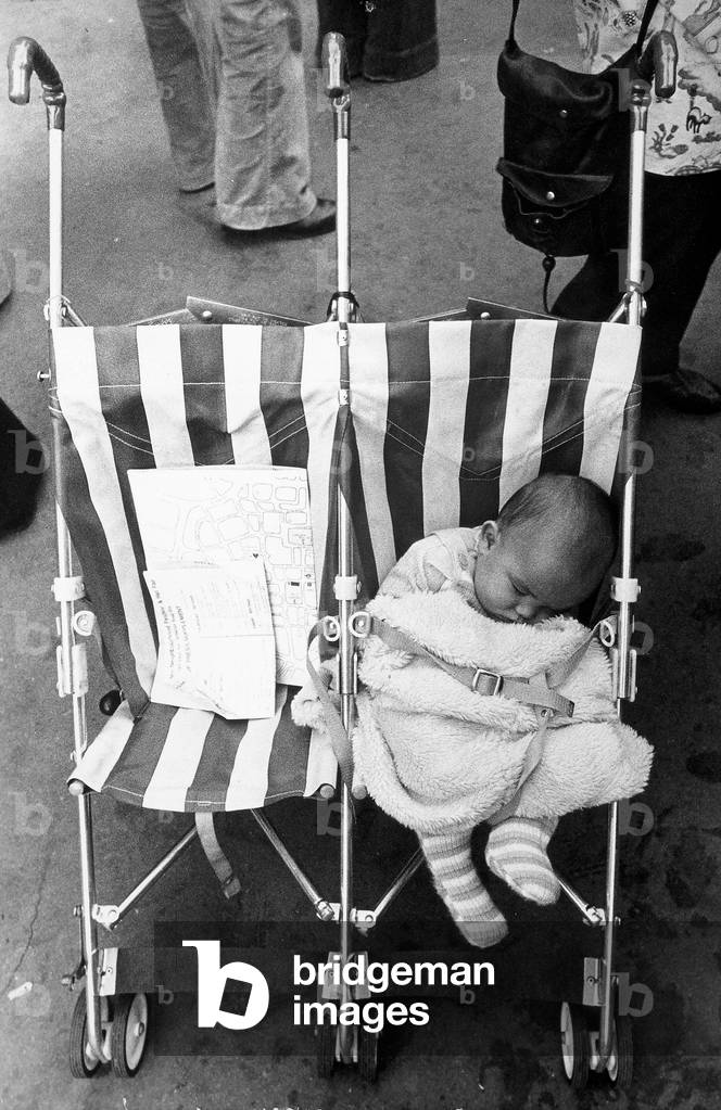 A sleeping infant in a stroller for twins