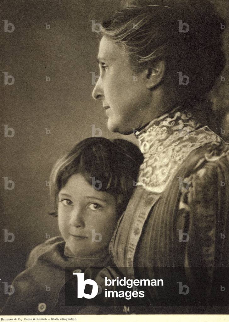 Half-length portrait of a child tenderly embraced by an elderly lady. The woman is posing with her face in profile, holding the little boy's chest. He has a lively and cheeky look, which is directed towards the camera