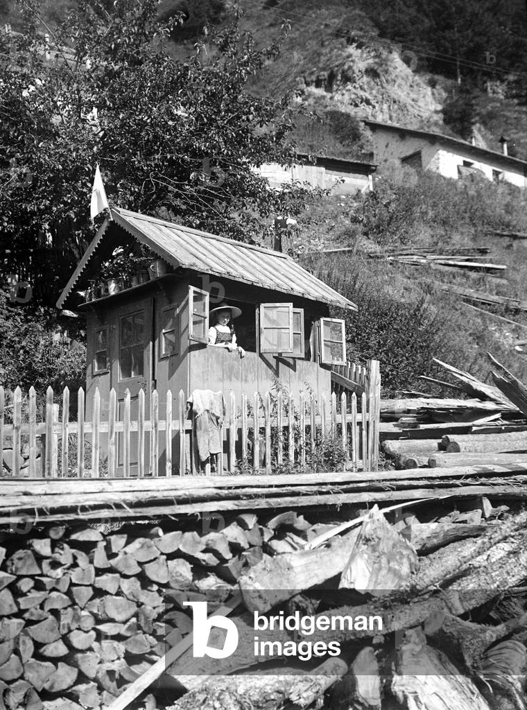 Little girl looking out the window of a wooden house, Tyrol