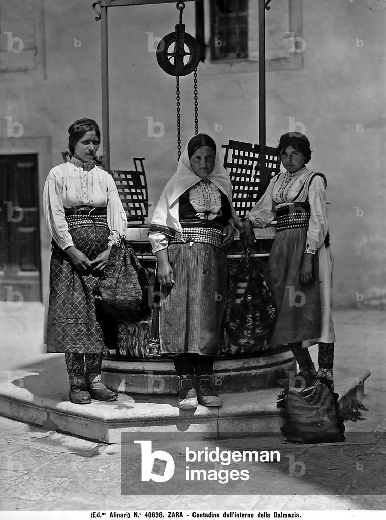 Three farmers from Dalmazia, in traditional costume in front of a well, Zara.