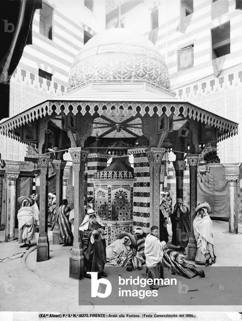 Men dressed as Arabs, seen near a fountain decorated for the Carnival festivities held in Florence in 1886