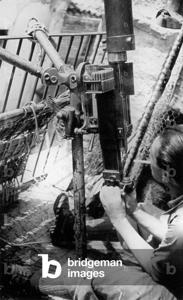 An Italian soldier of the Machine Gun Battalion in Spain, shown aiming a machine gun upwards (b/w photo)