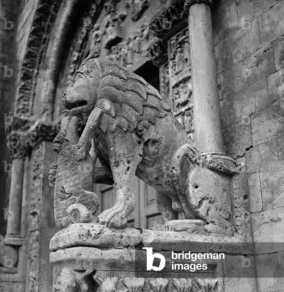 Column-bearing lion to the left of the middle portal of the Cathedral of San Michele, in Bitetto